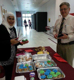 Friends of Sigma Tau Delta member Reem Al Hasawi selling a cupcake to former AUK President Win Thompson.